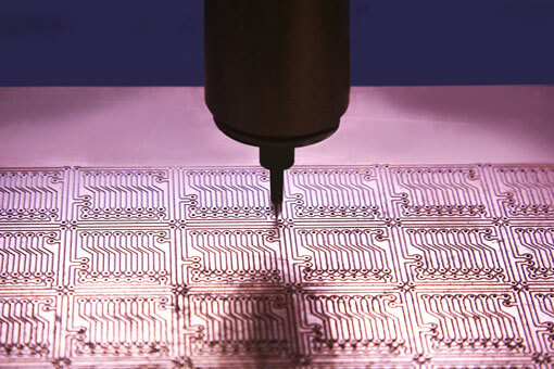 A laser drilling holes in microelectronic circuit board mounts